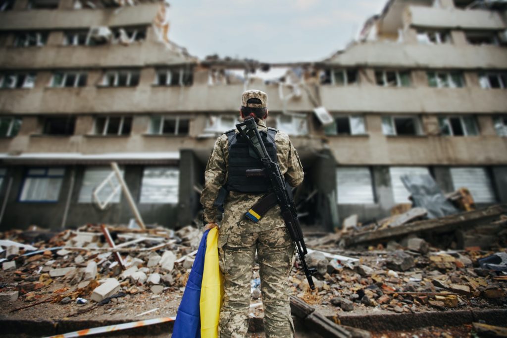 A soldier stands near a destroyed house. War in Ukraine