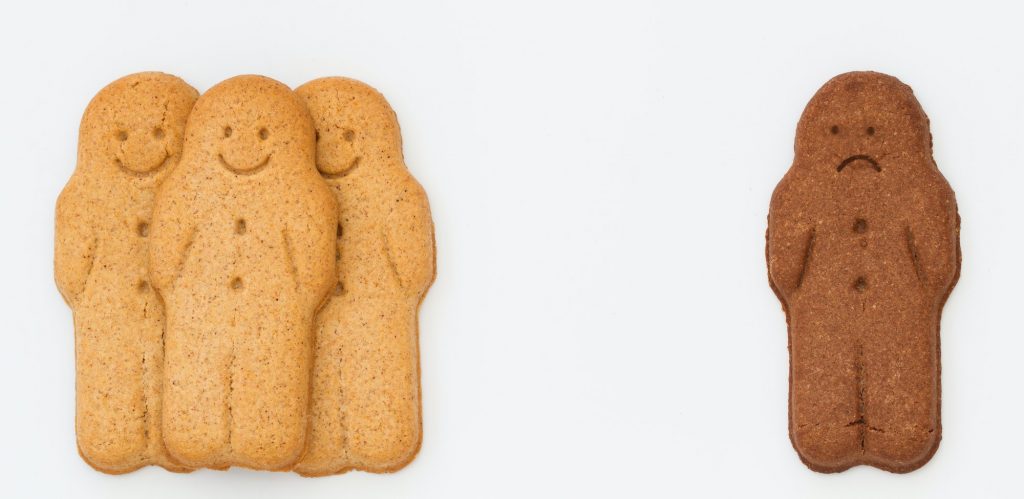 white gingerbread men and a sad black gingerbread man in kids racism and racial segregation concept